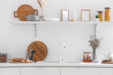 Beyaz tezgahlı, raflı, lavabolu ve çatallı modern mutfağın içi.