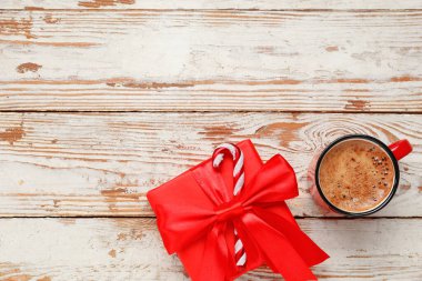 Beyaz ahşap arka planda hediye kutusu olan bir fincan kahve.