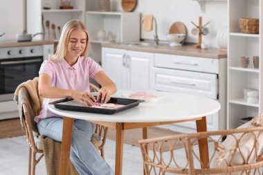 Mutfakta kurabiye paketleyen genç bir kadın. Göğüs kanseri farkındalığı konsepti