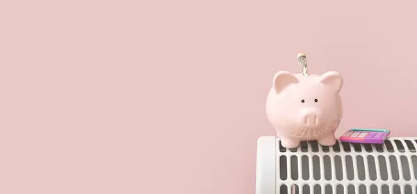 Piggy bank and calculator on electric heater against pink background with space for text. Heating saving concept