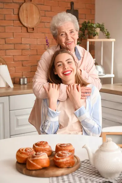 Senior woman hugging her grandmother in kitchen