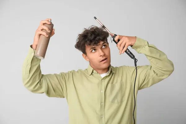 Pemuda Tampan Menggunakan Hair Spray Dan Curling Iron Pada Latar — Stok Foto