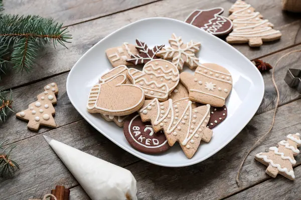 Plate with tasty Christmas cookies and cream on wooden table
