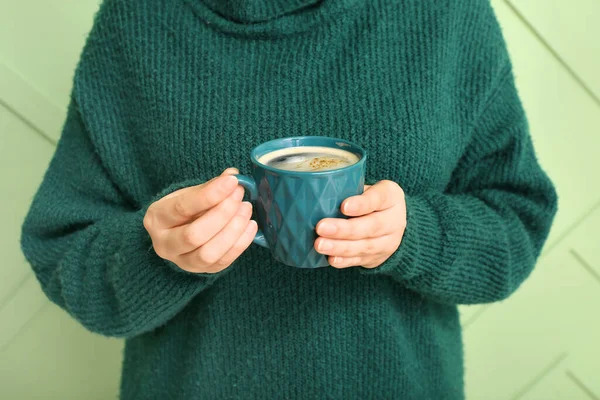 Woman with cup of coffee on green background