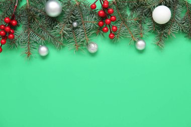 Köknar dalları, kırmızı böğürtlen ve yeşil arka planda Noel topları olan kompozisyon