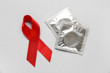 Kırmızı kurdeleli ve arka planda kondomlar. AIDS Günü konsepti
