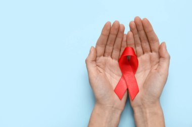 Mavi arka planda kırmızı kurdeleli bir kadın. AIDS Günü konsepti