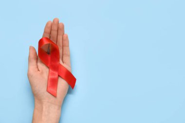 Mavi arka planda kırmızı kurdeleli bir kadın. AIDS Günü konsepti