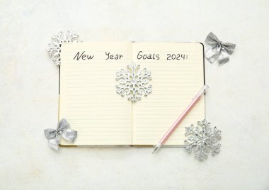 Yeni Yıl Hedefleri 2024, beyaz grunge arkaplan üzerine kalem ve gümüş Noel süslemeleri içeren defter