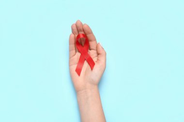 Mavi arka planda kırmızı kurdeleli bir kadın. AIDS Günü konsepti