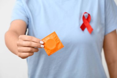 Tişörtünde kırmızı kurdele ve prezervatifli kadın, yakın plan. AIDS Günü konsepti