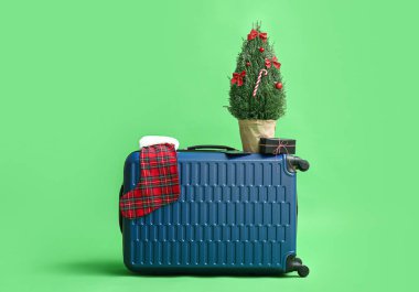 İçinde Noel ağacı olan bavul, yeşil arka planda hediye ve çorap