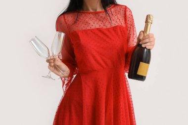 Beyaz arka planda bardakları ve bir şişe şampanyası olan güzel genç bayan, yakın plan.