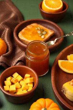 Kavanoz ve tost, yeşil ahşap arka planda balkabağı reçeli.