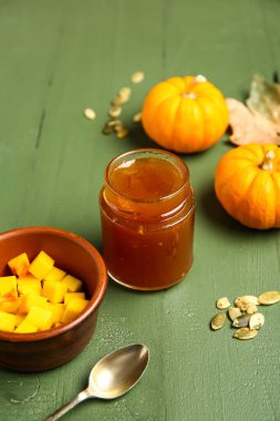 Kavanoz dolusu tatlı kabak reçeli ve yeşil ahşap arka planda tohumlar.