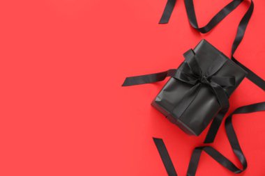 Kırmızı arka planda hediye kutusu ve kurdele. Kara Cuma