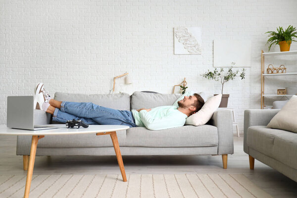 Молодой бородатый мужчина лежит дома на диване