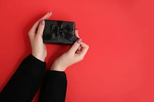 stock image Female hands with gift box on red background. Black Friday