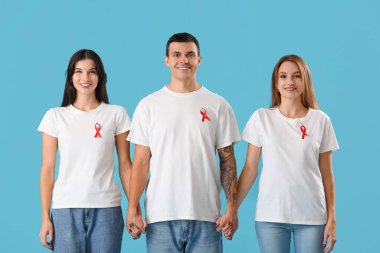 Mavi arka planda kırmızı kurdeleli bir grup genç. Dünya AIDS Günü konsepti