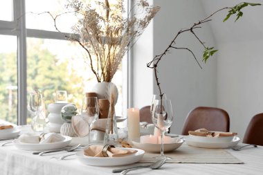 Evde kurumuş çiçekler, mumlar ve tabaklar olan zarif bir masa.