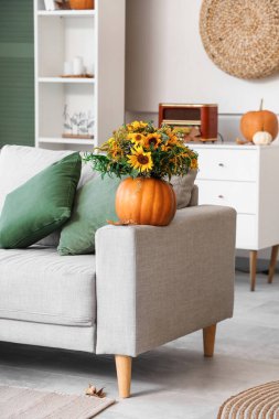 Oturma odasındaki kanepede sonbahar çiçekli balkabağı.