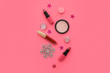 Farklı dekoratif kozmetik ürünleri ve pembe arka planda kar taneleri