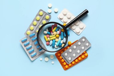 Mavi arka planda farklı haplar içeren büyüteç