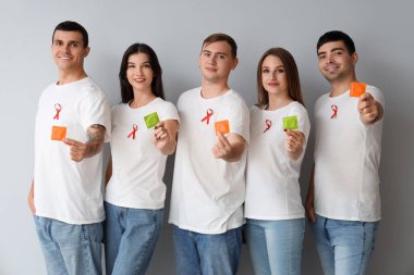 Gri arka planda kırmızı kurdeleli ve prezervatifli bir grup genç. Dünya AIDS Günü konsepti