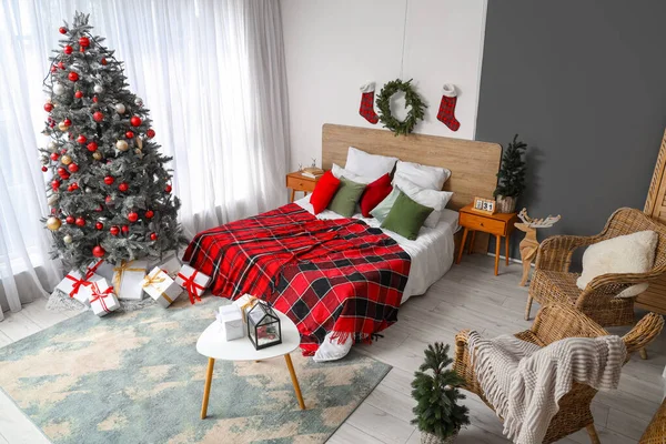 居心地のよいベッド クリスマス ツリー ギフト用の箱および平らな毛布が付いているお祝いの寝室の内部 — ストック写真
