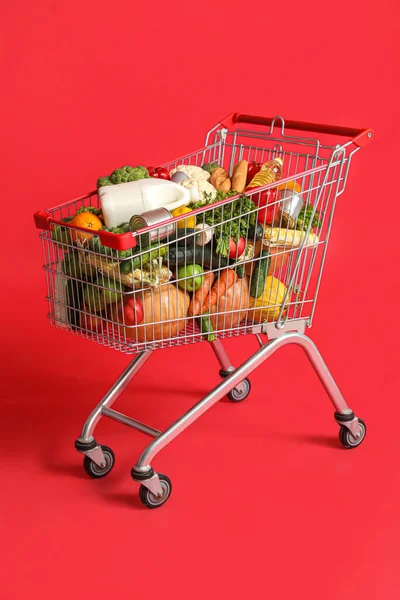 Shopping cart full of food on red background