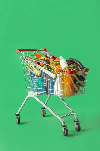 Shopping cart full of food on green background