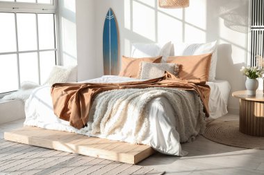 Sörf tahtası ve büyük yataklı modern bir yatak odası.