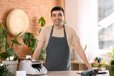 Erkek kasiyer çiçekçide para sayma makinesi kullanıyor.