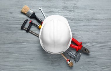 Gri ahşap arka planda inşaat aletleri ve miğfer seti
