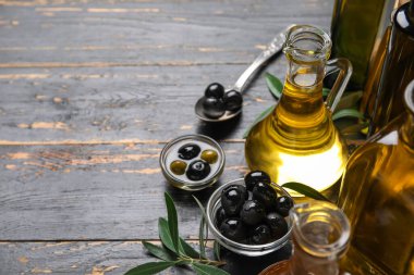 Siyah ahşap arka planda zeytin ve bir sürahi yağ.