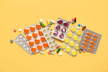 Sarı arka planda su toplayan paketlerdeki farklı haplar.