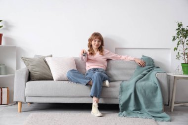 Genç kadın evde kanepede televizyon izlerken