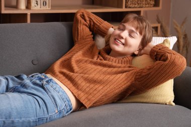 Evdeki kanepede dinlenen genç bir kadın.