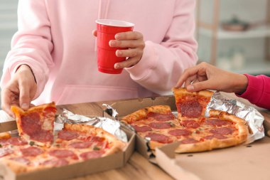 Mutfakta lezzetli biberli pizza yiyen genç çift, yakın plan.