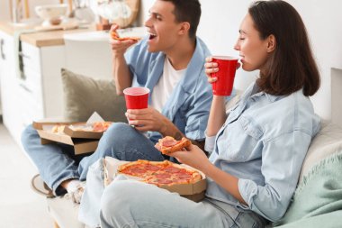 Evde lezzetli biberli pizza yiyen genç bir çift.