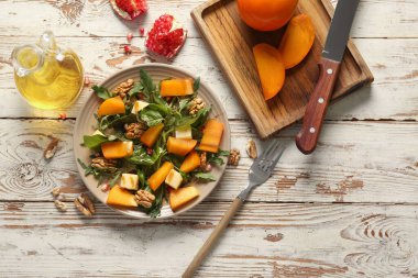 Beyaz ahşap arka planda hurma, ceviz ve nar tohumlu lezzetli bir salata tabağı.