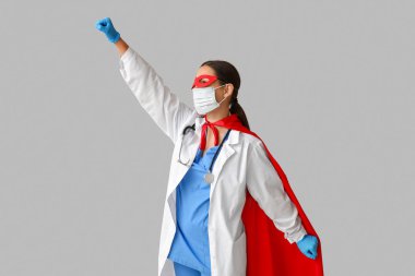 Süper kahraman kostümlü güzel bayan doktor ve beyaz arka planda tıbbi maske.