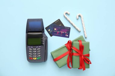 Kredi kartlı ödeme terminali, Noel hediyesi kutuları ve mavi arka planda şeker kamışları
