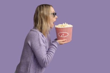 Üç boyutlu gözlüklü, mor arka planda patlamış mısırlı genç bir kadın.