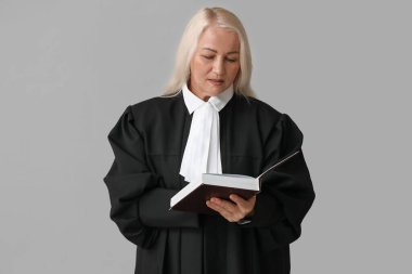 Gri arka plan kitabı olan olgun bir kadın yargıç.