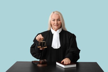 Adalet terazisi ve mavi arka plan kitabı olan olgun bir kadın yargıç.