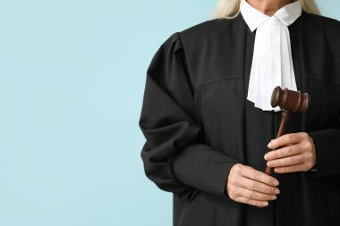 Mavi arka planda tokmağı olan kadın yargıç.