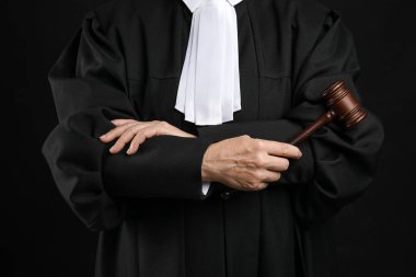 Çapraz kollu kadın yargıç ve siyah arka planda tokmak
