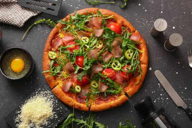 Domatesli lezzetli pizza ve siyah arka planda roka.