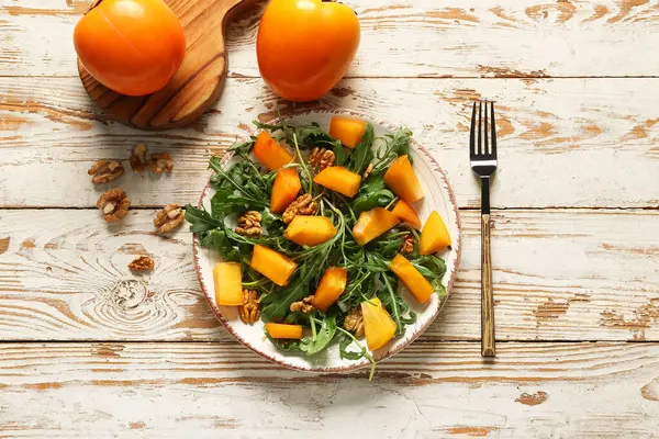 Plaat Van Heerlijke Salade Met Persimmon Walnoot Witte Houten Ondergrond — Stockfoto